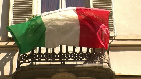 Patriotic Italian flag fluttering from a balcony with white flowers in Turin, Italy