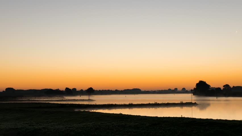 Time lapse of the sunrise at the river Lek with boats near Culemborg, The Netherlands.