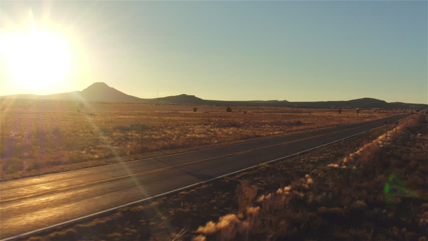 AERIAL: Black SUV car driving along empty country road at golden summer sunset. People traveling, road trip on historic Route 66 through beautiful meadow desert scenery in sunny summer Royalty-Free Stock Footage #16115923