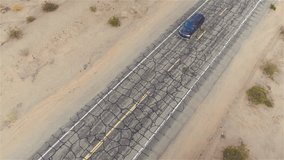 AERIAL: Black SUV car driving along old historic Route 66 through the vast desert. People traveling, road trip on empty cracked countryside road through America on sunny summer vacation - Powered by Shutterstock - Get 15% off with code: PIKWIZARD15