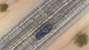 AERIAL: Black SUV car driving along old historic Route 66 through the vast desert. People traveling, road trip on empty cracked countryside road through America on sunny summer vacation - Powered by Shutterstock - Get 15% off with code: PIKWIZARD15
