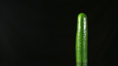 woman's hand dress the condom on cucumber