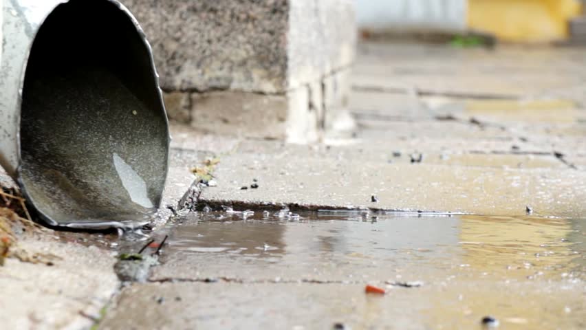 Rain Water Running out from an water outlet pipe onto the Pavement on a rainy day. | Shutterstock HD Video #16121683
