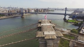 Aerial shot of Brooklyn Bridge. Camera flying around a top place of Brooklyn Bridge with flapping American flag. 