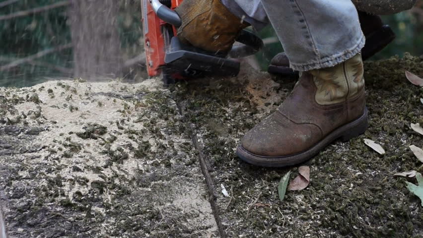 Closeup of the feet of a man operating a large chain saw
