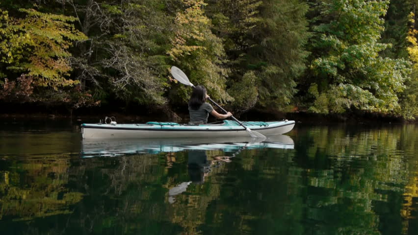 kayaker paddles through scenic lake with reflections