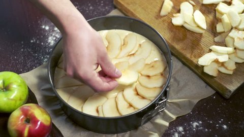 Preparing for baking apple pie. Cook puts apple slices in baking dish. Ingredients for baking apple cake. Sliced apples on cake batter : vidéo de stock