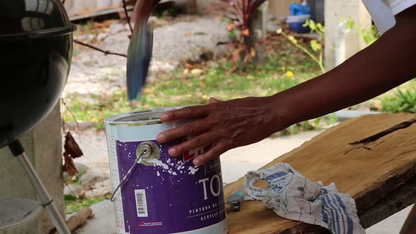 Artist stirring paint in paint can with paint brush
