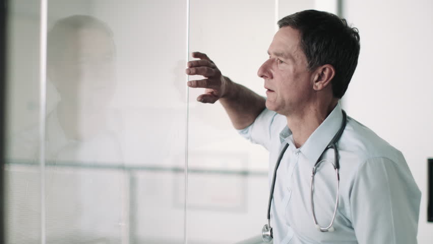 Mature Adult Male Doctor in Hospital looking out of window Royalty-Free Stock Footage #16154419