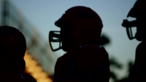 Silhouetted football players close up