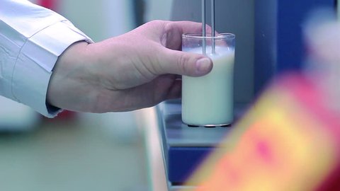 Milk analysis. Analysis of milk sample on laboratory equipment. Modern equipment. Scientist put glass with milk in laboratory equipment for research. Food quality test