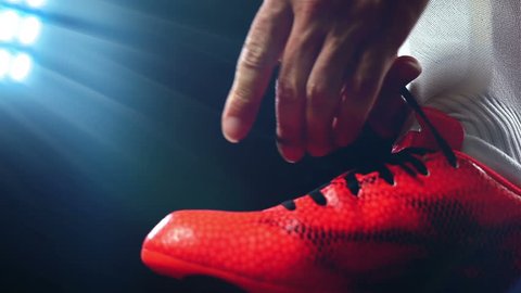 Football, soccer game. Professional footballer buckle his red shoes, slow motion