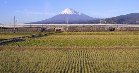 Japan, Honshu, Mount Fuji, Shinkansen Bullet Trains passing through harvested rice fields below the snow capped volcano - 01/12/2015