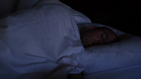 A man is asleep in the hotel bed at night