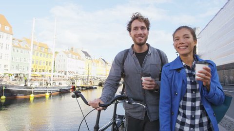 Copenhagen couple. People walking in Nyhavn, old port. Famous tourist attraction destination in Denmark Young multiracial happy couple with bicycle bike and coffee.