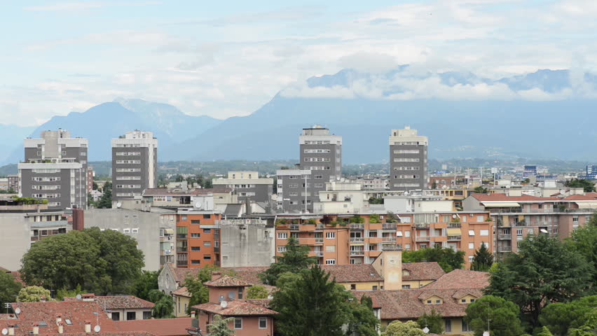 Populated area next to Mountain range. Landscape of a fantastic Italian city Udine with  the highest and most extensive mountain range system that lies entirely in Europe - Alps in the background.
