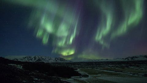 Bright aurora borealis northern lights realistic movement snowy mountains Iceland 4k