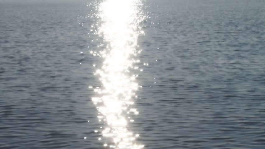 Scintillating reflections of the sun in a band on the surface of water, shot