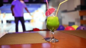 Green cocktail on a table on the background of man playing bowling - Powered by Shutterstock - Get 15% off with code: PIKWIZARD15