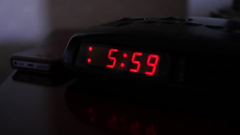 A digital alarm clock turns to six o'clock