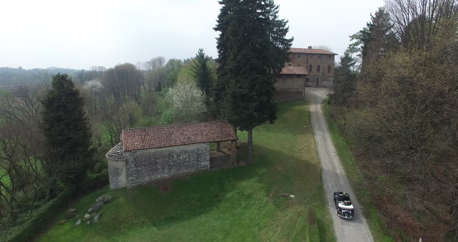 A married couple arrives with an Italian old car Maggiolino to a farm, a big house on a hill, just like a castle