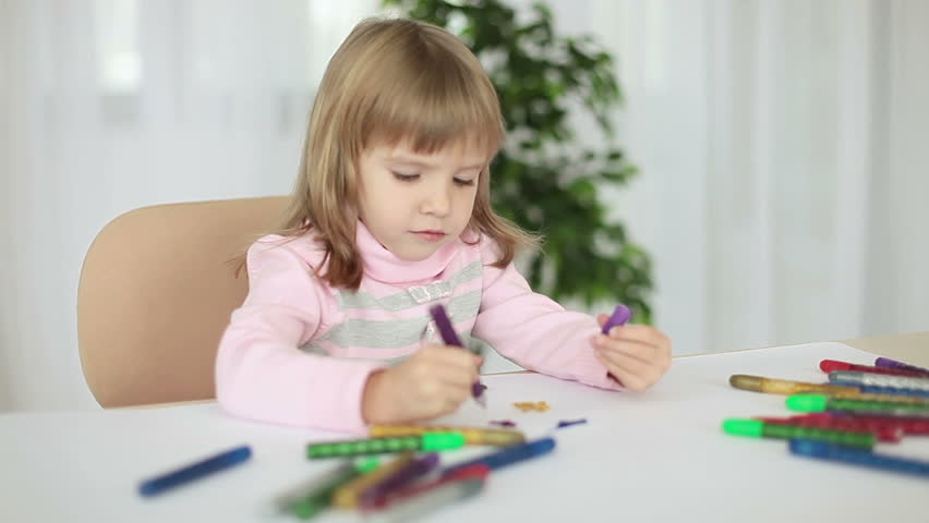 Child draws markers at the table 