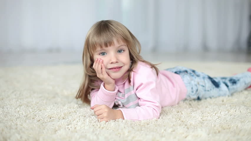 Happy child lying on a carpet. Looking at camera 