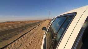 Camera attached on the side of the car driving on deserted highway. POV of car driving on desert highway