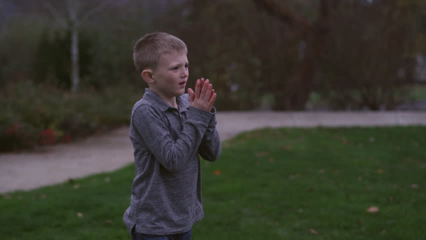 Father and son passing a football in a park at night, slow motion