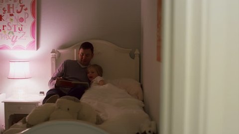 A father reads his daughter a bedtime story