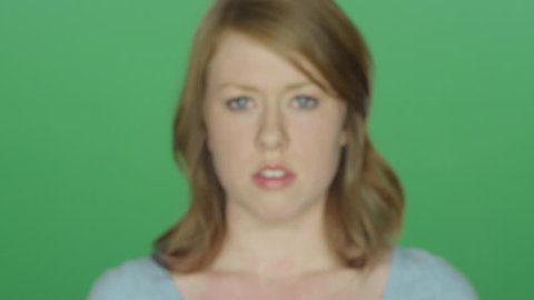 Beautiful brunette woman looking upset, on a green screen studio background