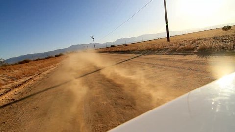 Camera attached on the back of a car while driving on desert dirt road