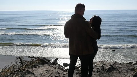 Man kissing woman silhouette against sun - cliff with sea view slow motion 2