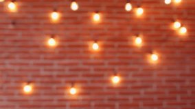 Video of real blurry brick brown wall with bright lamp lights. Christmas (Xmas) or New Year abstract holiday bright colorful bokeh background. 