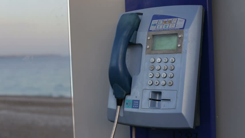 Female hand picks up the phone dials the number of a payphone on the street