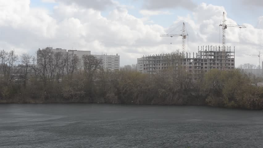 The beginning of the rain on the lake on the background buildings under construction.
