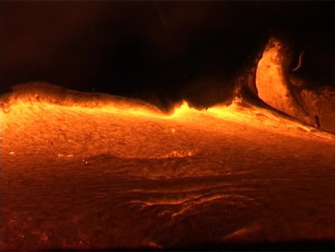 Molten lava oozes from a volcano, erupting eerily into domes belching flames.