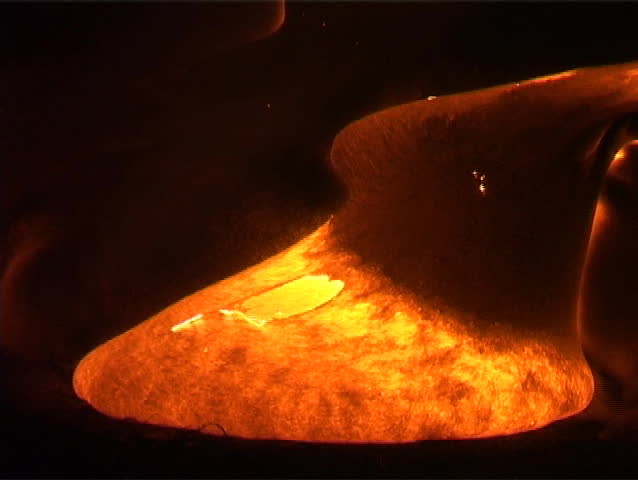Molten lava oozing down a volcano shoots up flames along its leading edges.