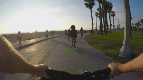 VENICE BEACH, CA/USA: March 19, 2015- Viewpoint POV point of view of bicycle rider. A bike rider navigates a narrow beach path, sharing it with other cyclists, joggers, and skateboarders.