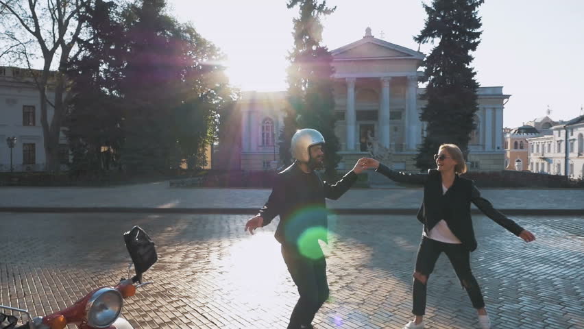 Happy young hipster couple dancing and having fun in old city center, slow motion