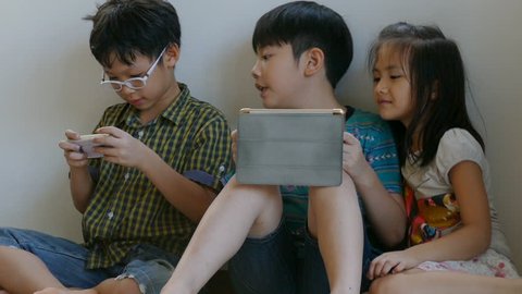 Young asian boys playing online games on tablet computer and smart phone
