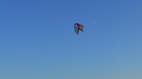 CLACTON-ON-SEA, ESSEX, ENGLAND - 22ND AUGUST 2015: View of a kite used for surfing flying high in a clear blue sky. A half moon can be seen just behind it.