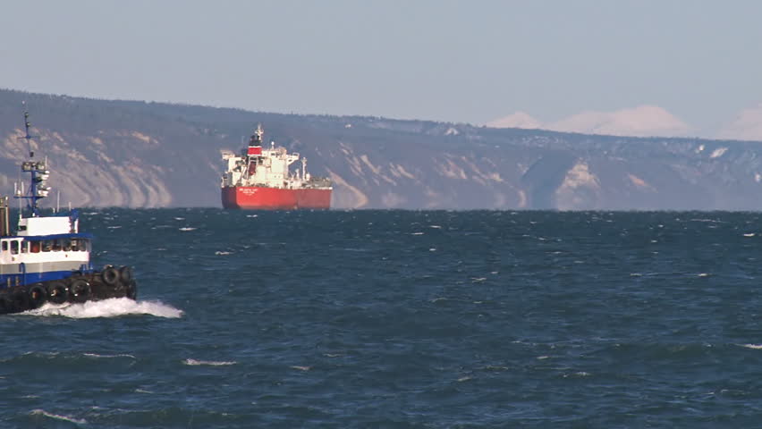 Working tug Redoubt approaching, an oil tanker at anchor in the background.