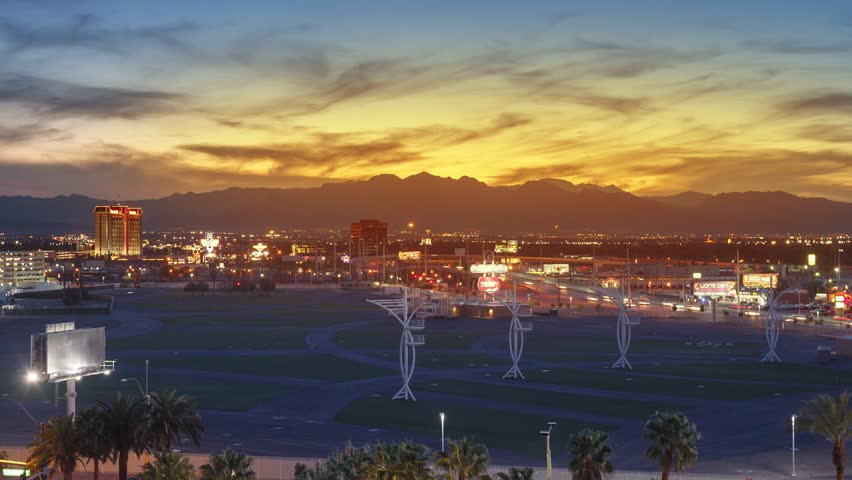 Las Vegas Strip traffic with city of Las Vegas cityscape in background changing from sunset to night. 4K UHD Timelapse. Zoom out.