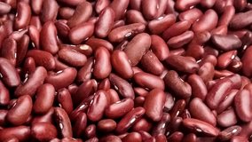 Closeup macro of natural red kidney beans, dehydrated legumes, being scooped up with a wooden spoon, slow motion 30p
