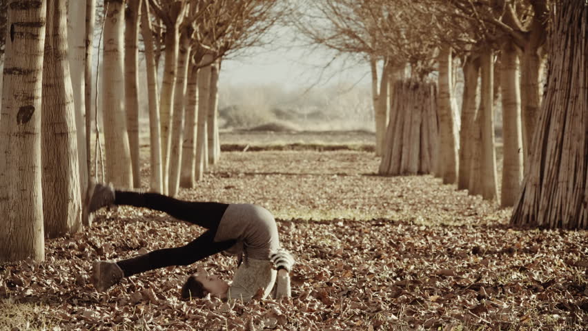 Woman exercizing yoga in Greek nature,grass field,tall trees.A woman doing yoga exercizes outside in nature in the beautiful Greek mountain village of Goura