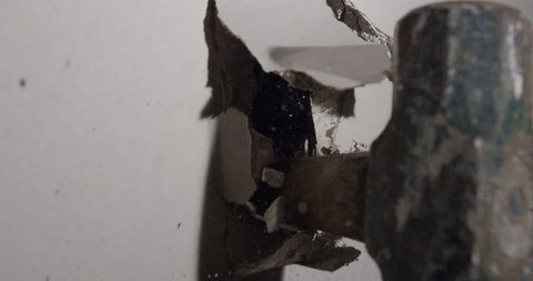Slow motion hammer smashing through drywall in house renovations