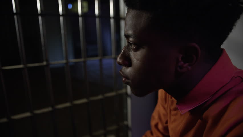 Young man looking out from his prison cell through the bars of jail Royalty-Free Stock Footage #16329001