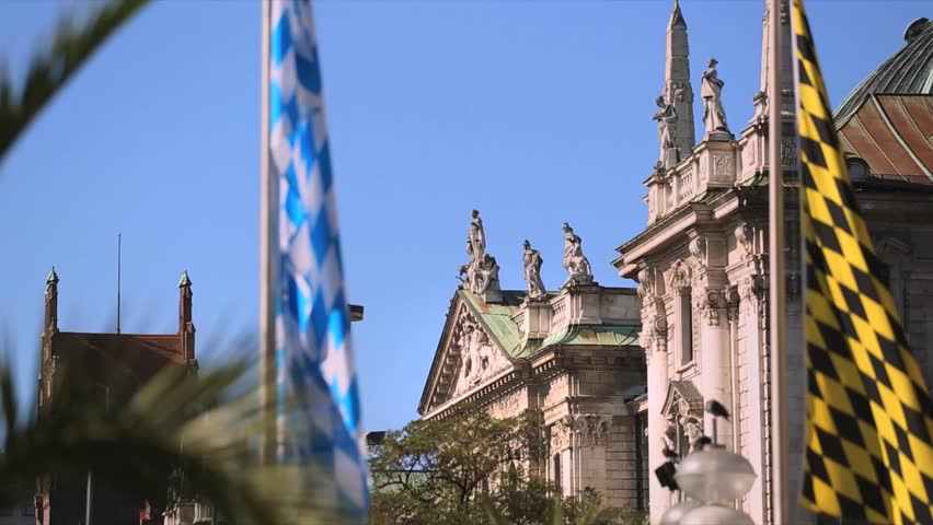 The Karlsplatz in the center of Munich, Germany, with the flags of Bavaria (blue white) and Munich (yellow black). The building in the background is the Bavarian state ministry of justice.