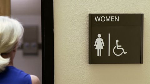 woman walking into a womans restroom in an office